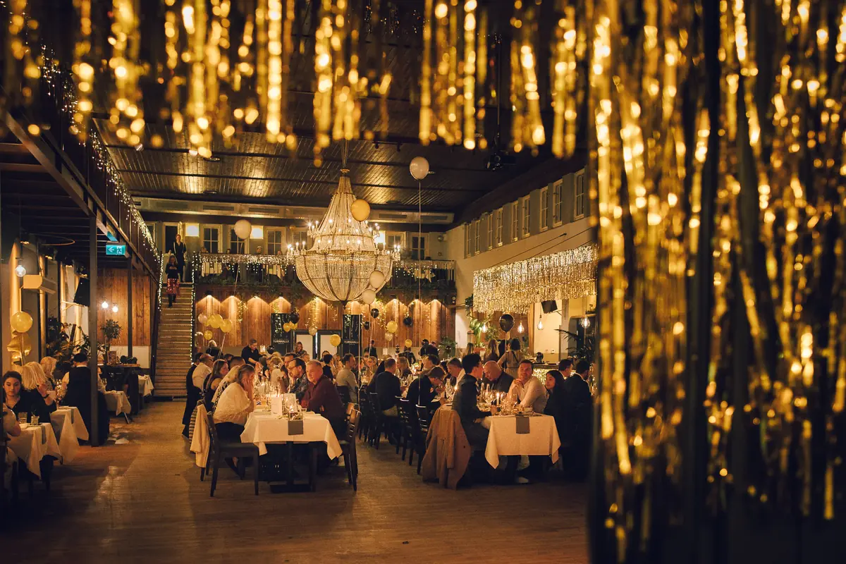 Dinnergäste im festlich geschmückten Saal der Alten Turnhalle Berlin